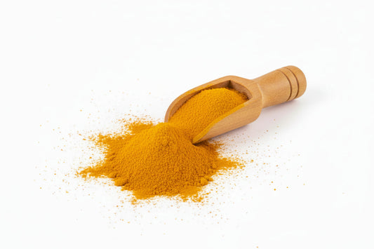 Cúrcuma en polvo de color naranja con cuchara de madera, sobre fondo blanco.
